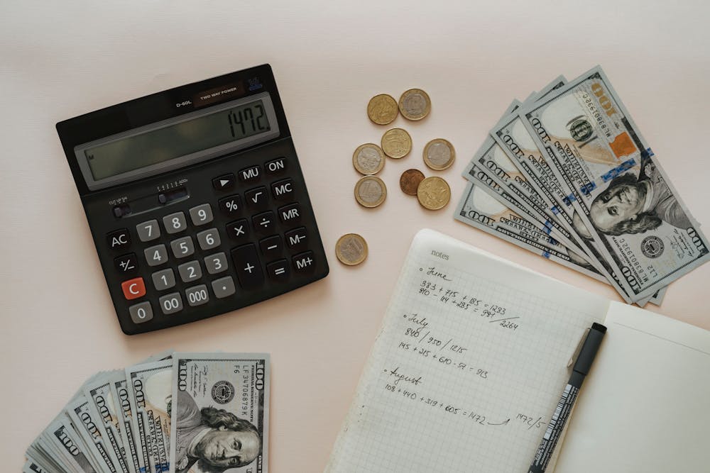 budgeting with dollars notebook, coins, and calculator