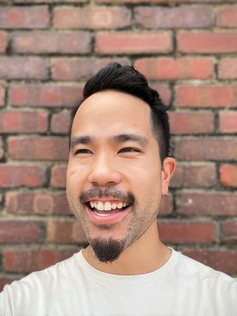 Head shot of Warren Wong with brick wall background