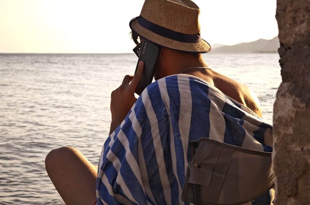 man on phone looking over ocean at sunset